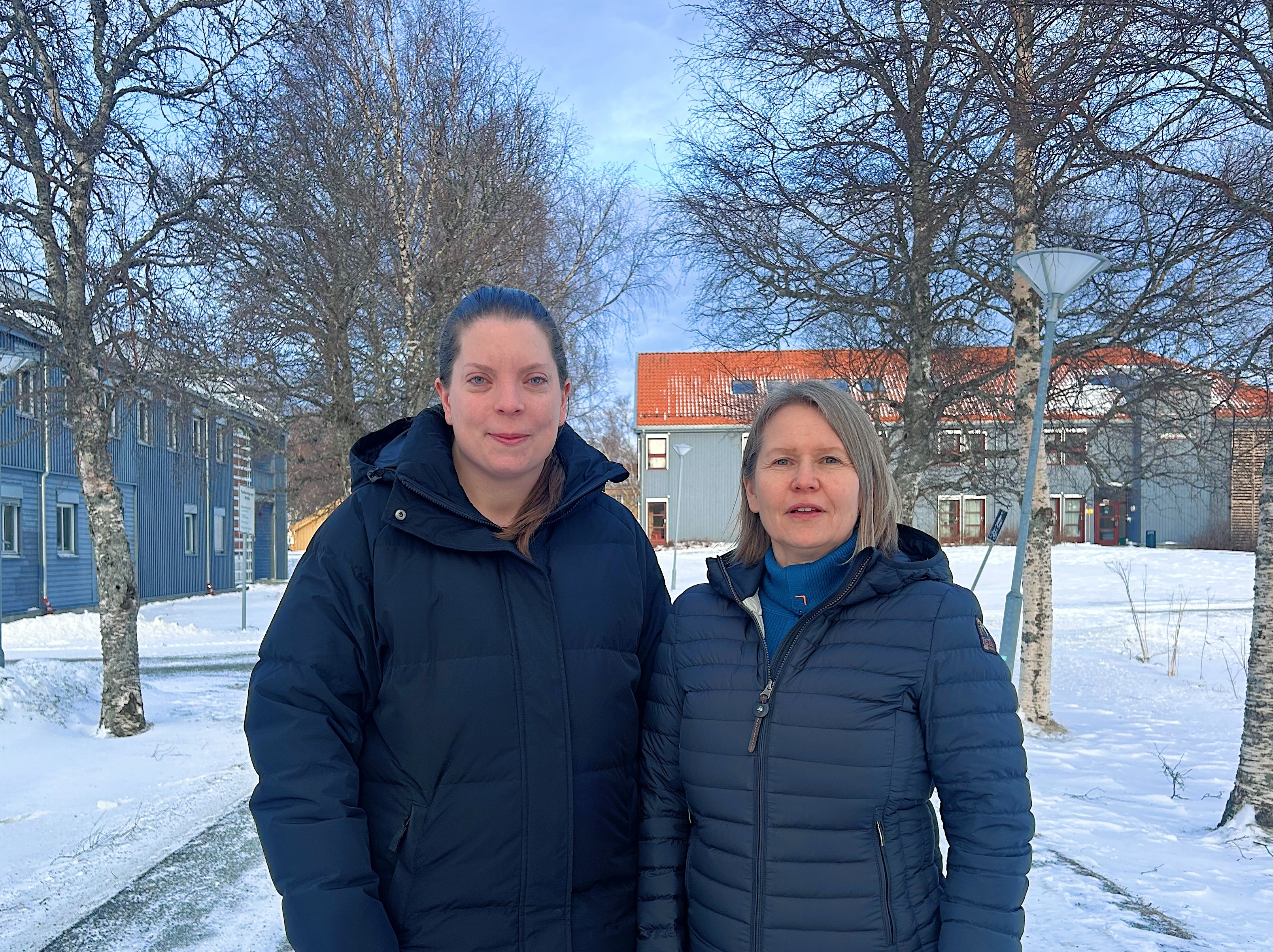 Regine Ringdal og Lena Westby står foran bygninger på Låven på Dragvoll og ser inn i kamera. Fotografi.