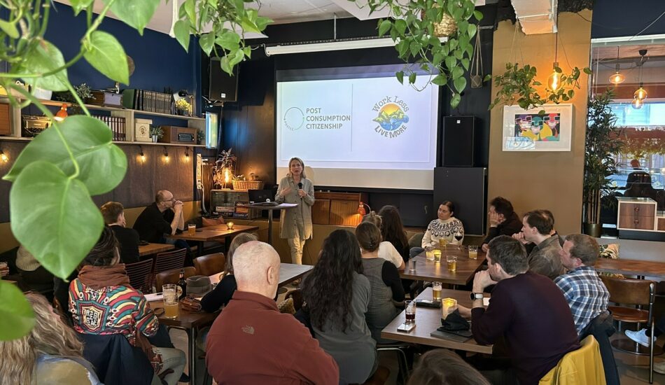 Fotografi av seminarlokale med mennesker som er vendt mot et lerret. Forsker Berit Nilsen presenterer Post Consumption Citizenship.